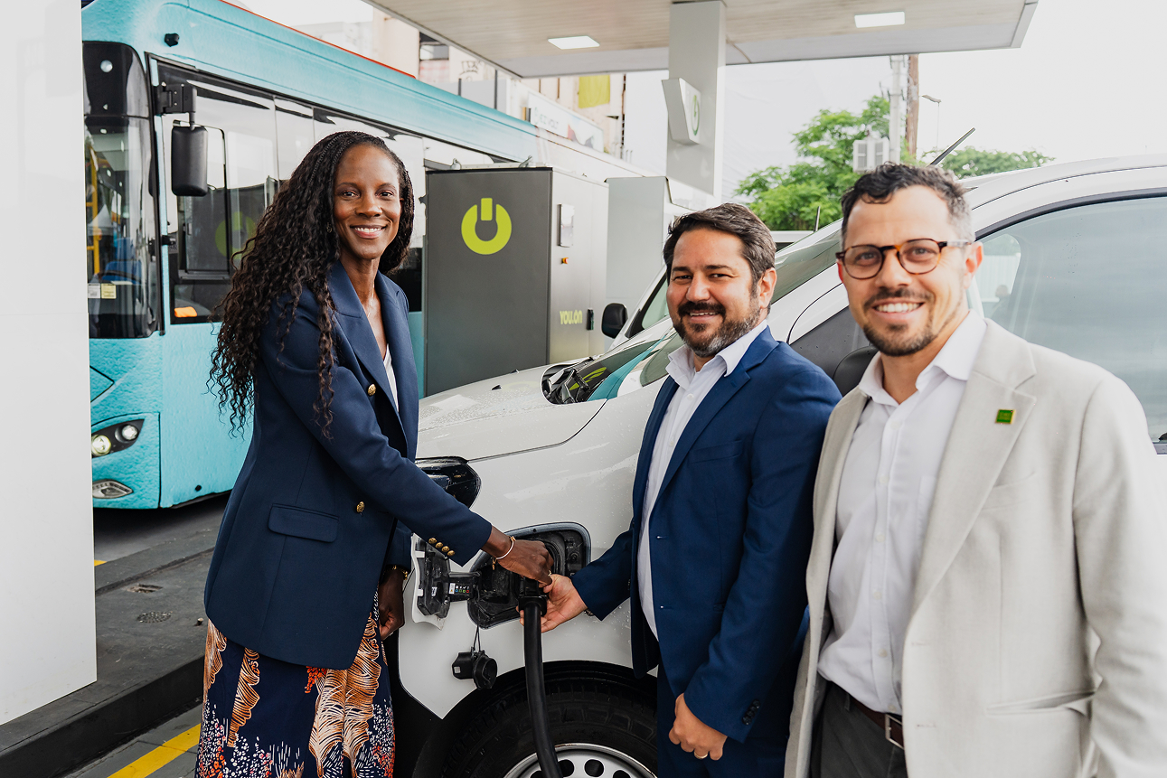 Three people staring at the camera while they charge an electric vehicle