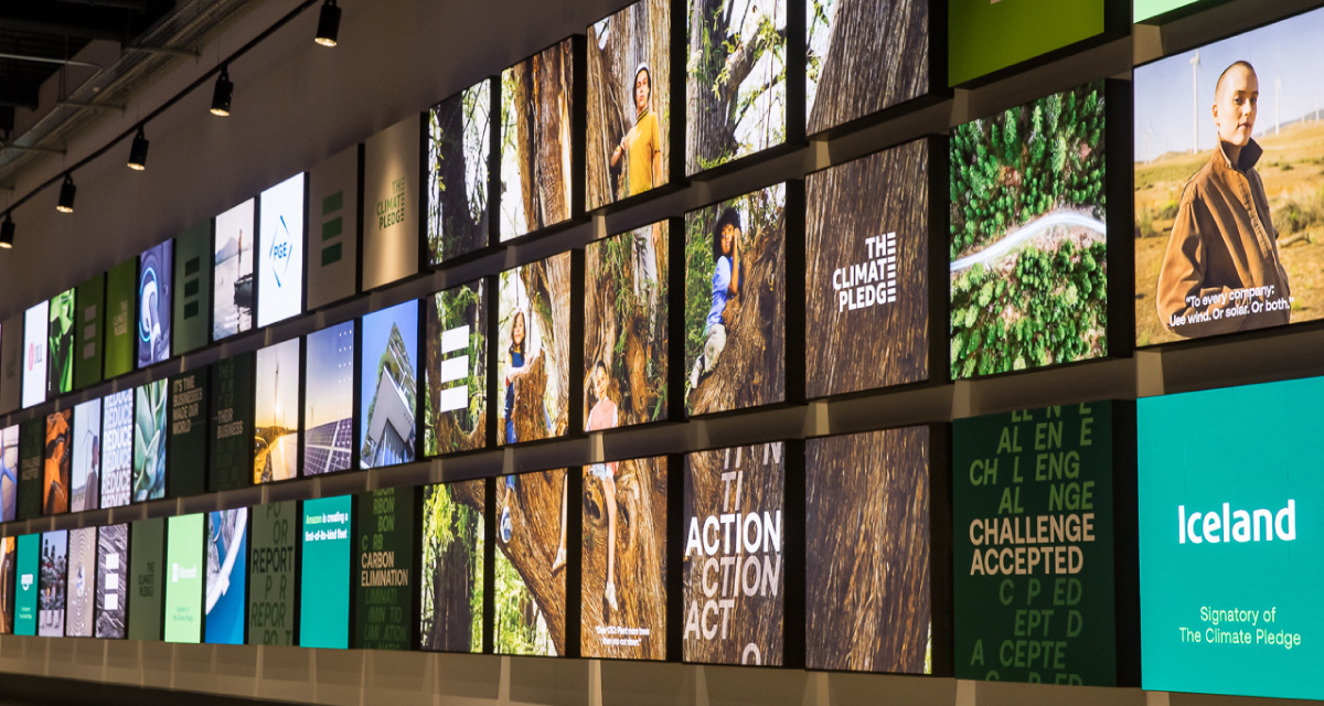 Rotating digital displays at Climate Pledge Arena featuring The Climate Pledge signatory achievements.