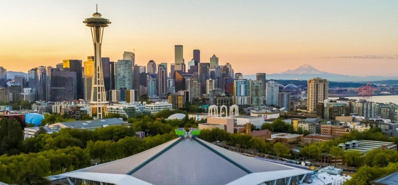 Overhead image of Climate Pledge Arena with the Space Needle, Seattle city skyline, and Mount Rainier in the background