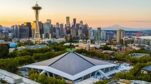 Overhead image of Climate Pledge Arena with the Space Needle, Seattle city skyline, and Mount Rainier in the background