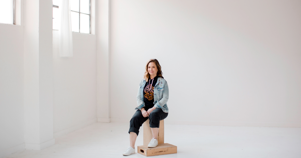 Artist Jen Ament in the “S” Kraken logo sweatshirt and enamel pin sets she designed for The Climate Pledge Collection.