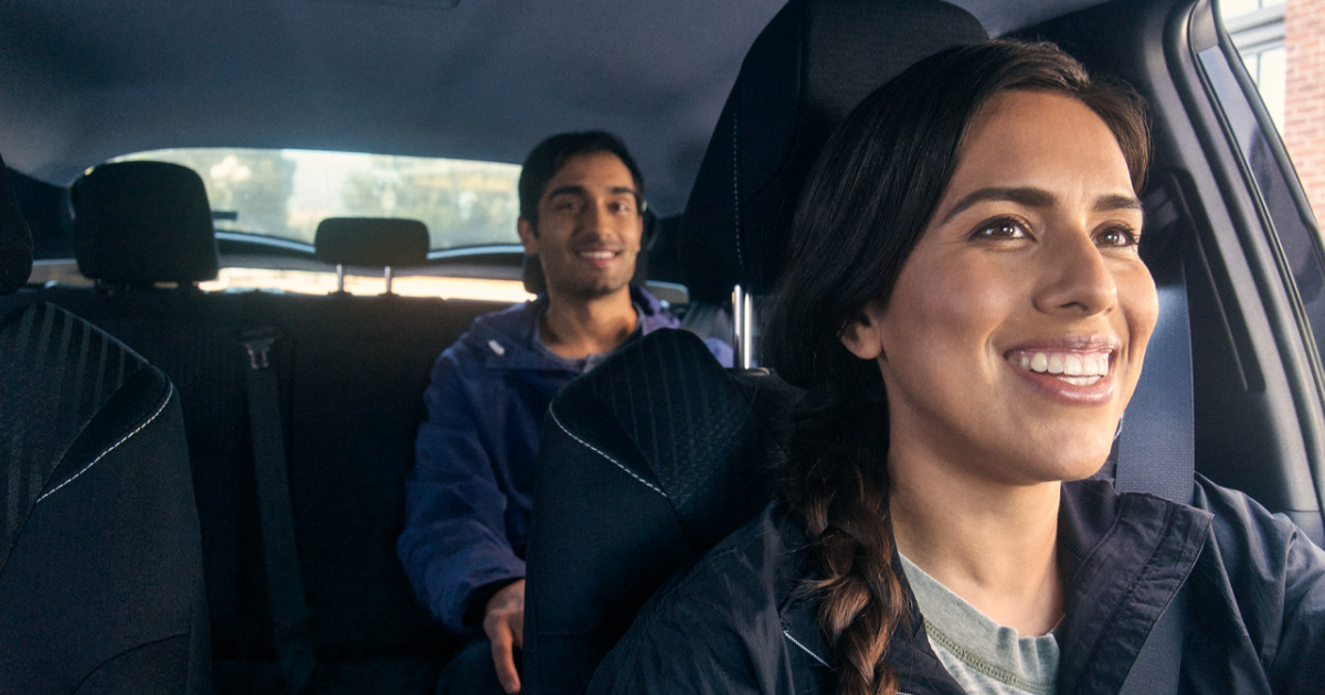 An Uber driver smiles at her back passenger in the rear view mirror. 